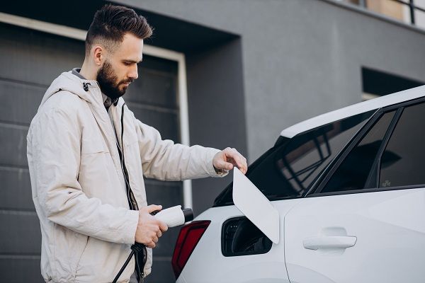 homme qui utilise une borne de recharge à son domicile